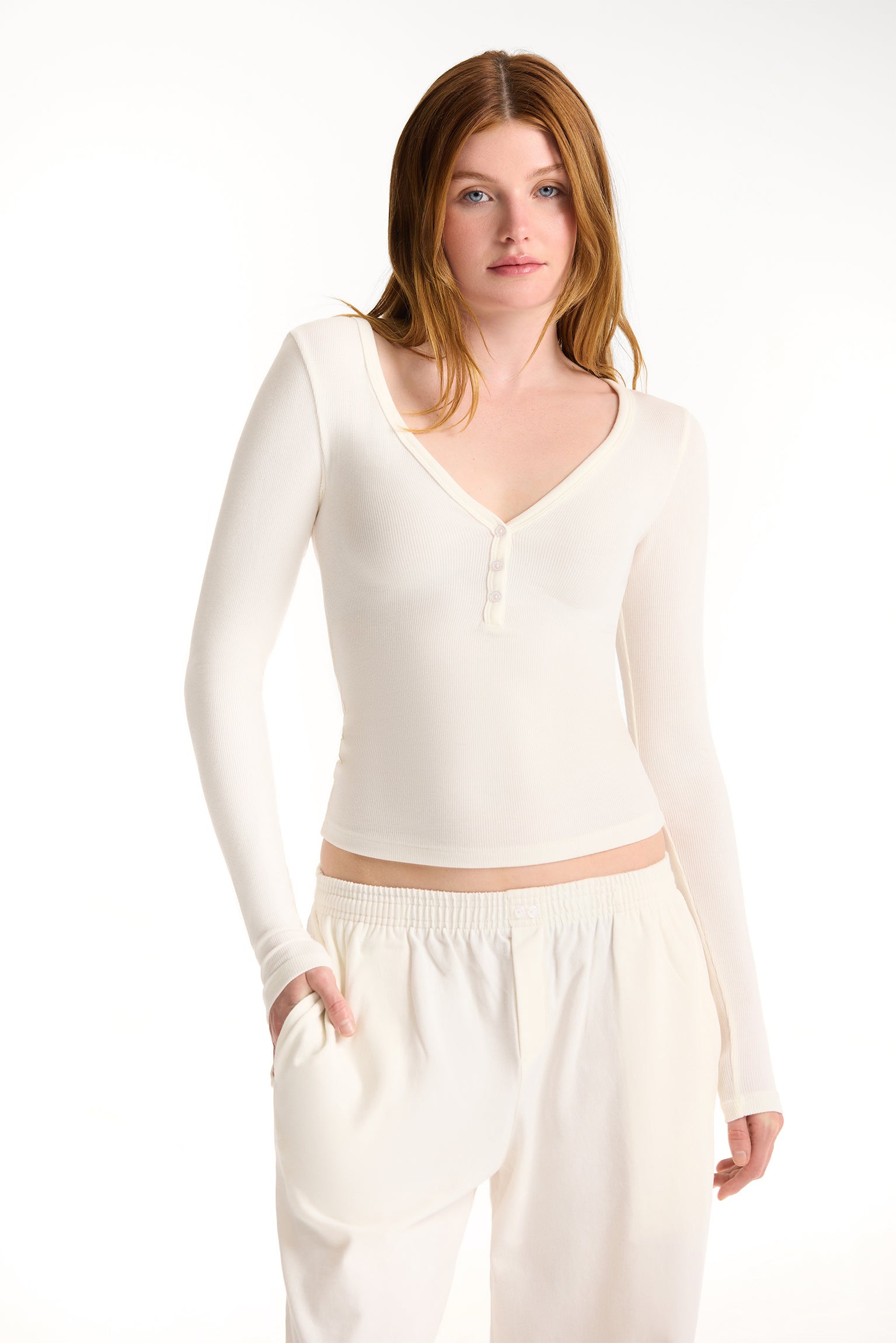 Woman wearing a white long-sleeve top and pants on a white background 