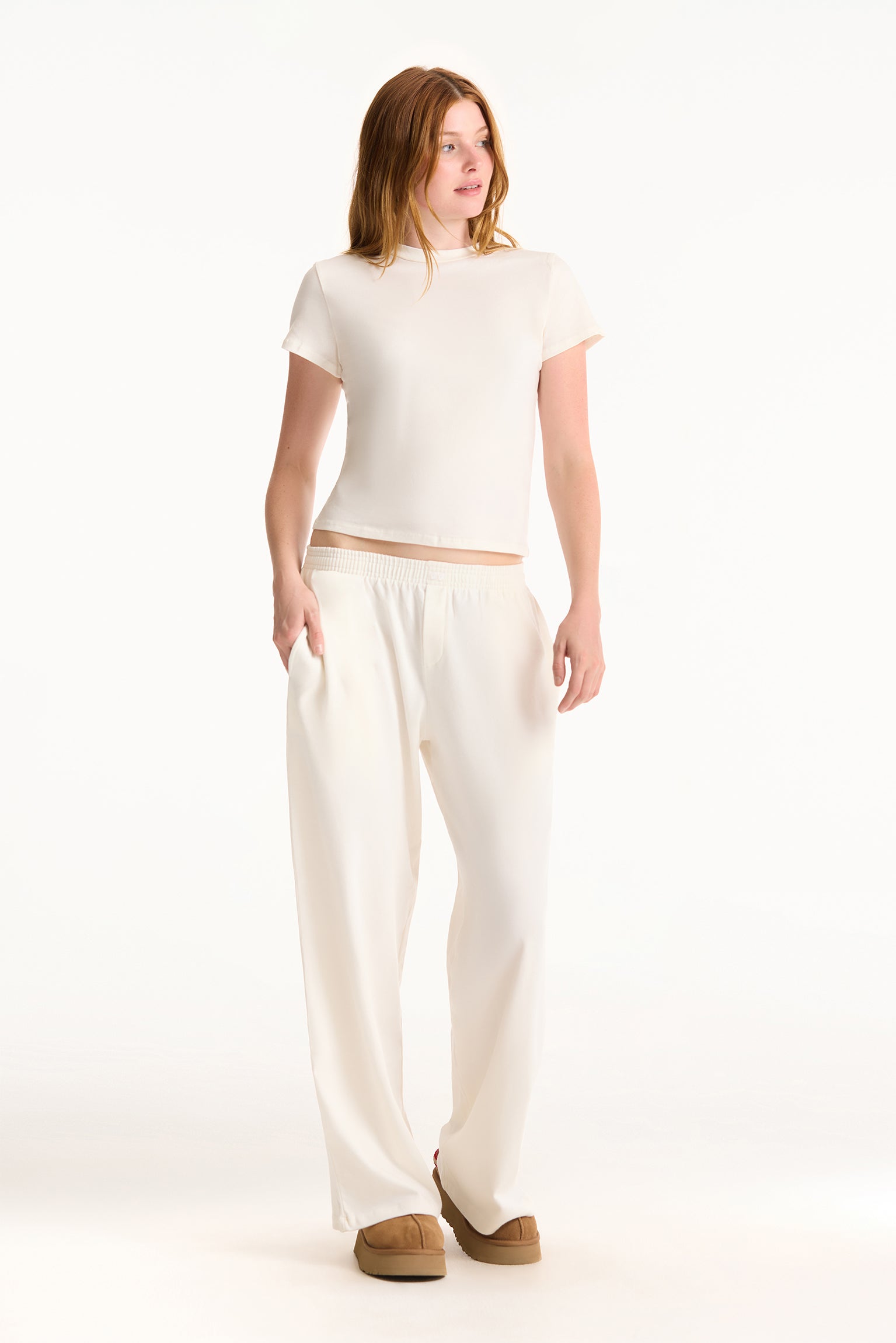 Woman wearing a white top and pants on a white background