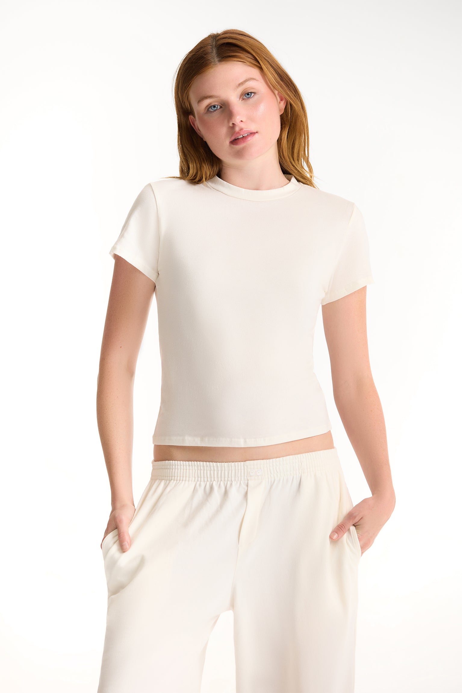 Woman wearing a white crop top and pants on a white background <model-info>Dickey wears a size S and is 5’9”, 24” waist, 32” bust.</model-info>