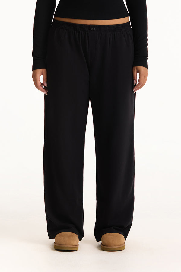 Black pants worn by a person on a white background 