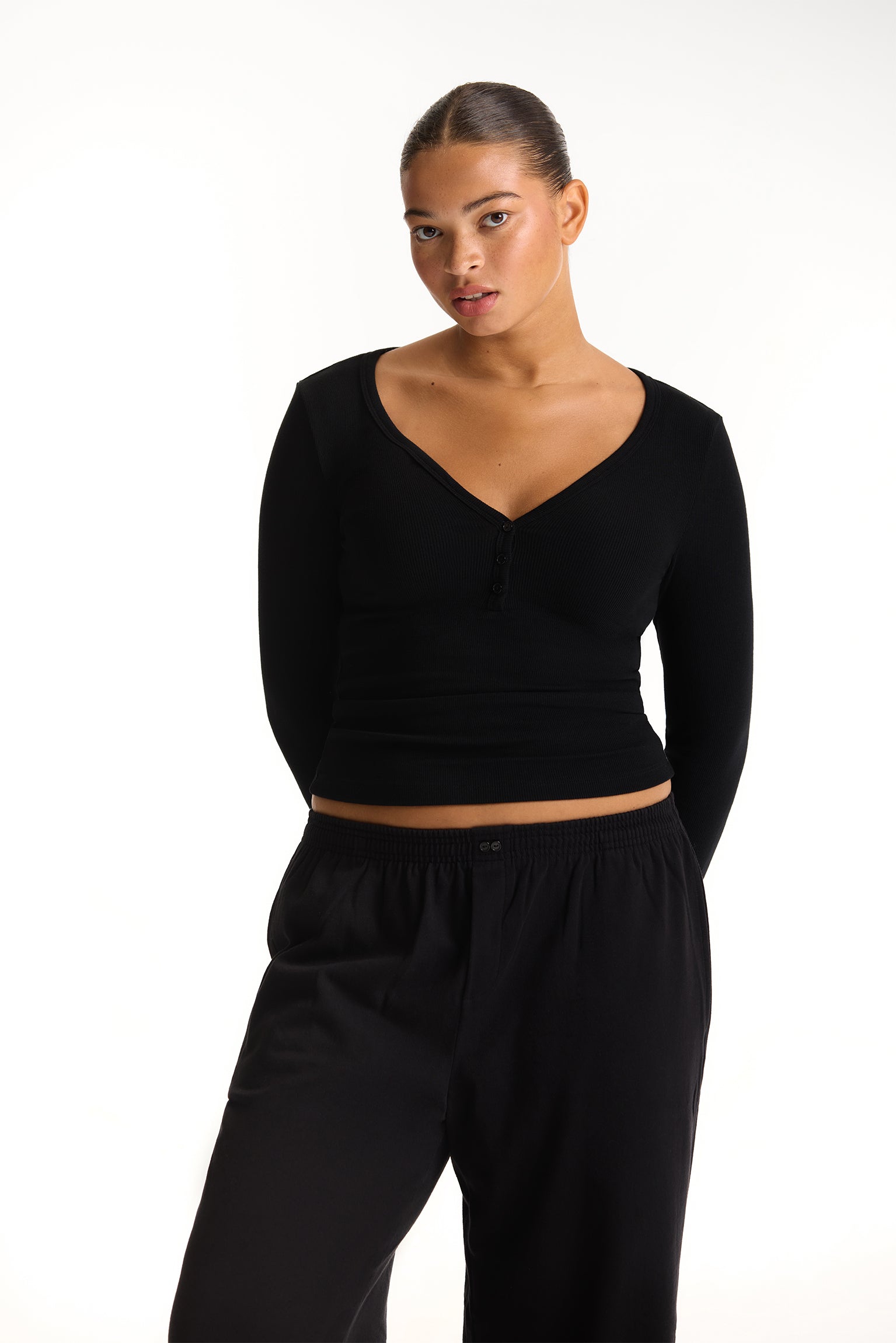 Woman wearing a black crop top and pants on a white background <model-info>Jade wears a size L and is 5’9”, 30” waist, 38” bust.</model-info>