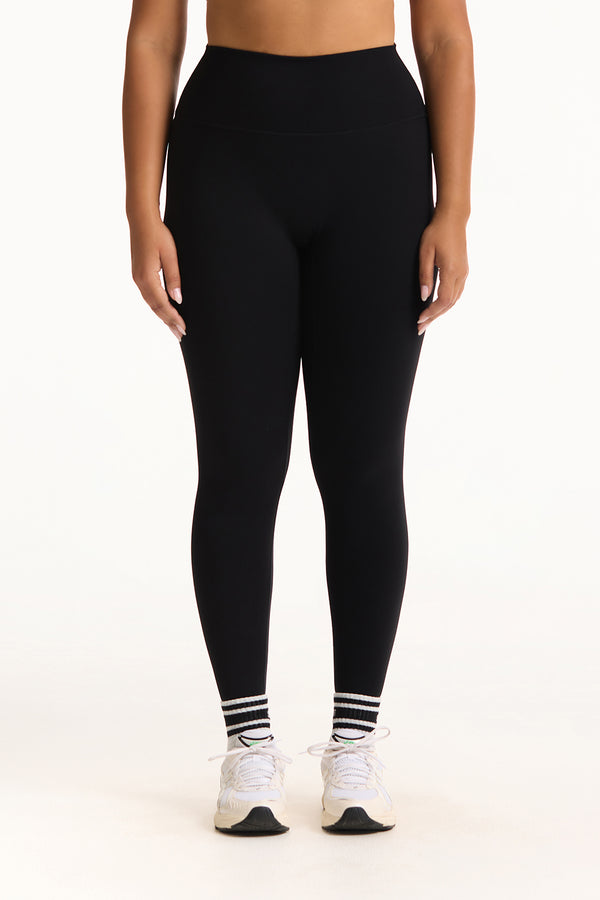 Person wearing black leggings with white sneakers on a white background