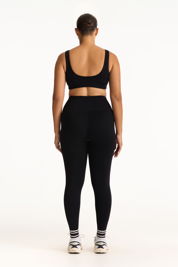 Person wearing a black sports bra and leggings set on a white background