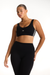 Woman wearing a black sports bra with white stripes and matching leggings on a white background