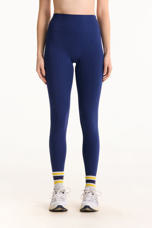 Person wearing navy leggings with white and yellow accents on a white background
