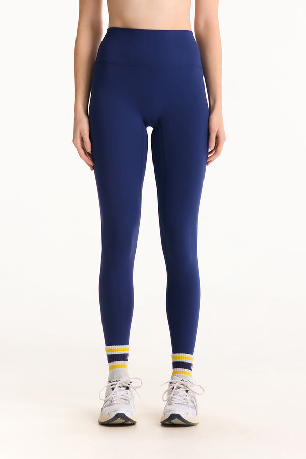 Person wearing navy leggings with white and yellow accents on a white background