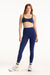 Woman wearing a blue sports bra and leggings with yellow accents on a white background