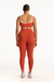 Person wearing an orange sports bra and leggings set on a white background