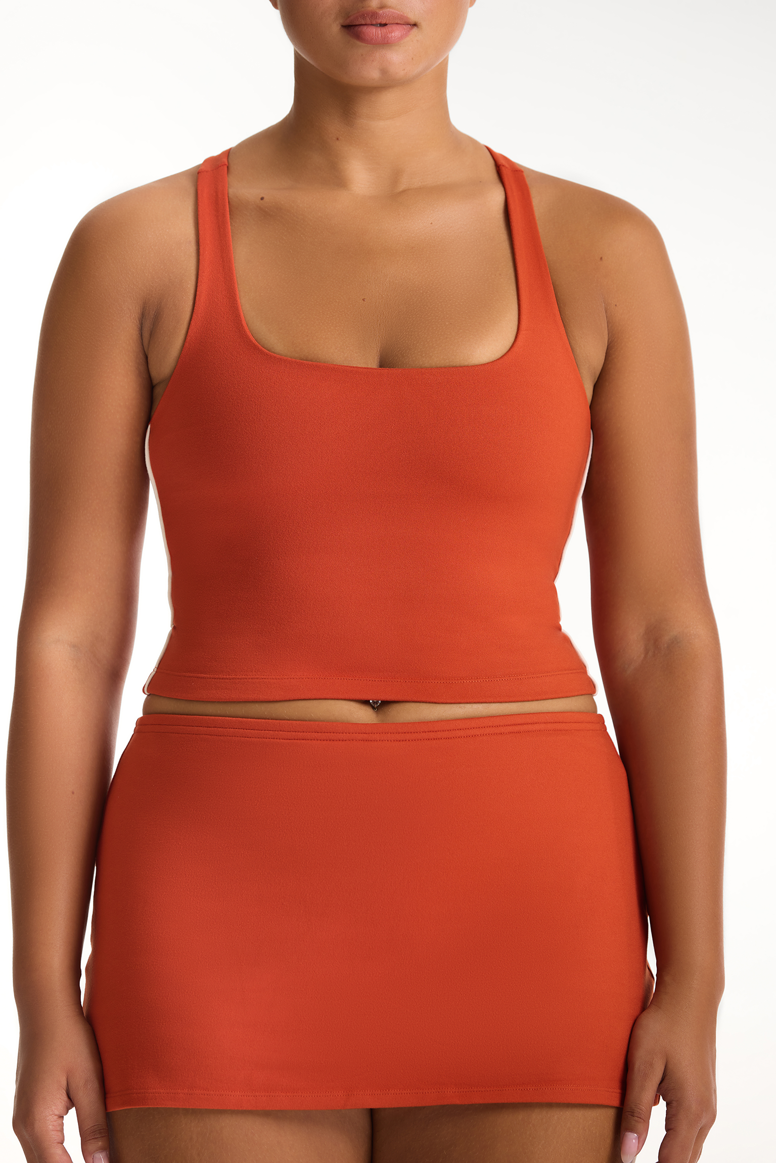 Person wearing an orange tank top and skirt set on a white background