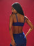 Woman wearing a blue sports bra and leggings with a red background