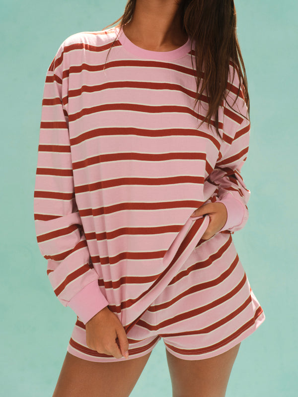 Person wearing a pink and brown striped pajama set against a light blue background