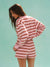 Woman wearing a pink and red striped outfit against a light blue background