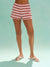 Person wearing pink and white striped shorts on a light blue background