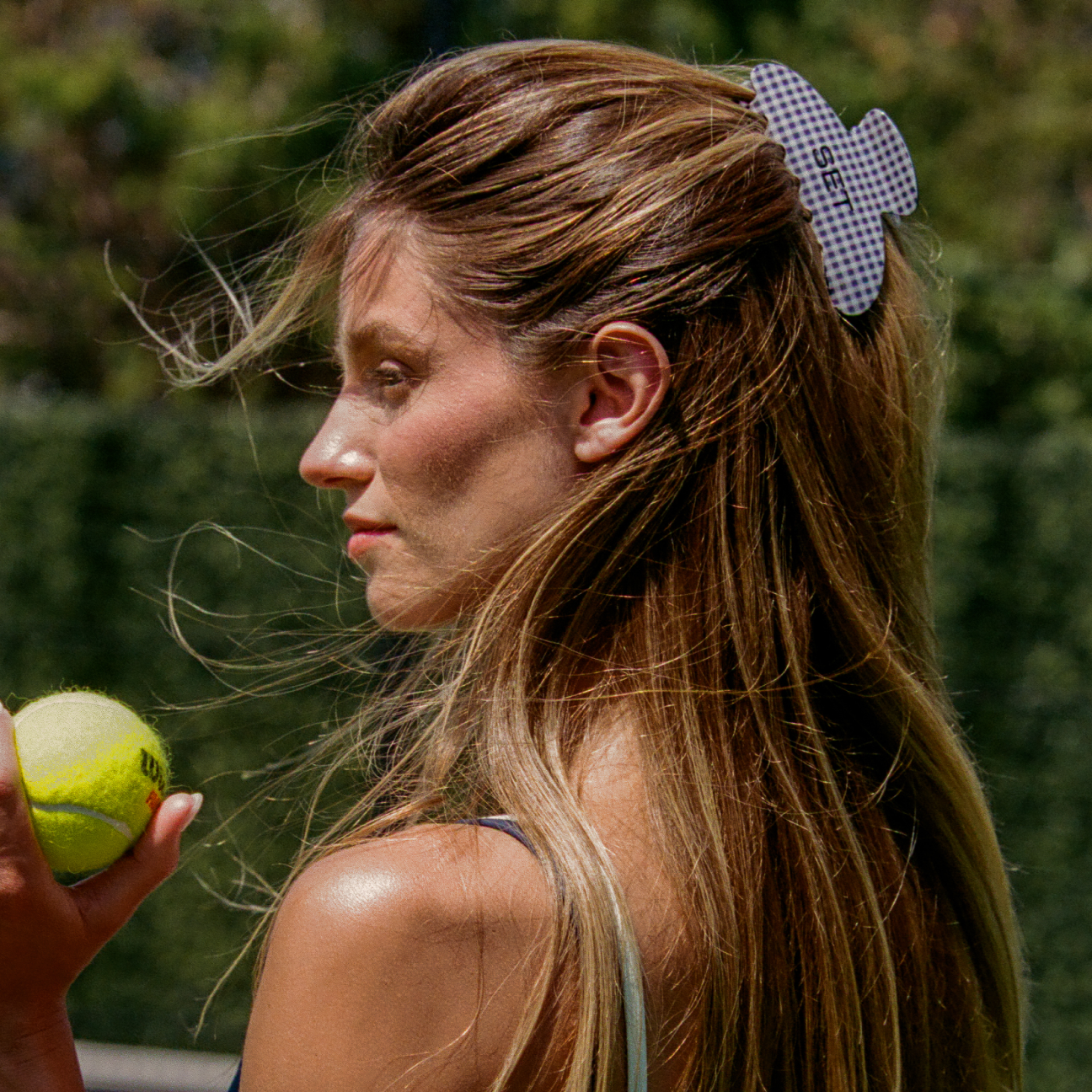 Woman wearing hair clip while holding tennis ball