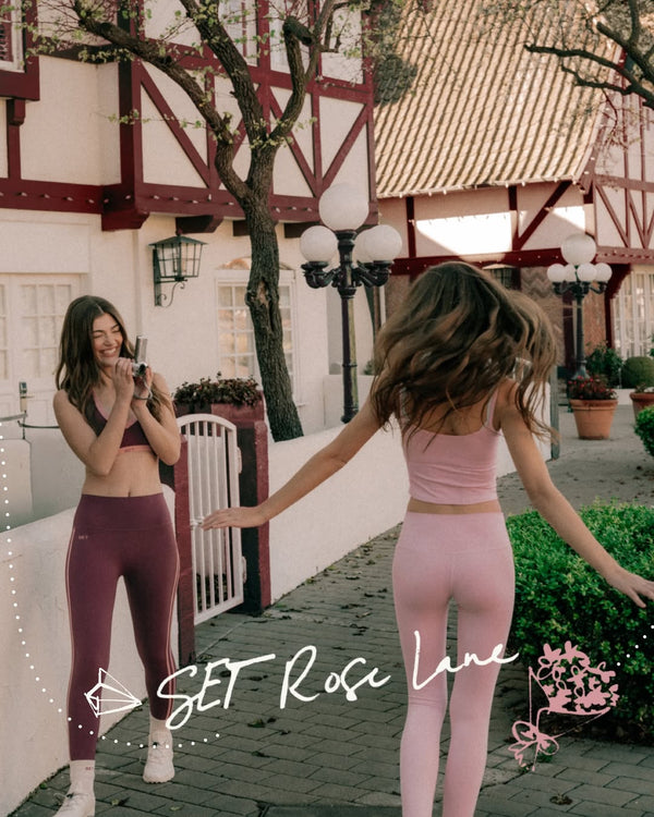 Two women in matching athletic wear standing outdoors with a building in the background.