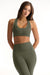 Woman wearing an olive green sports bra and leggings set on a white background <model-info>Sophie wears a size S and is 5’9½”, 23” waist, 34CD bust.</model-info>