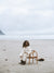 Girl wears cream outfit while sitting on a chair on the beach