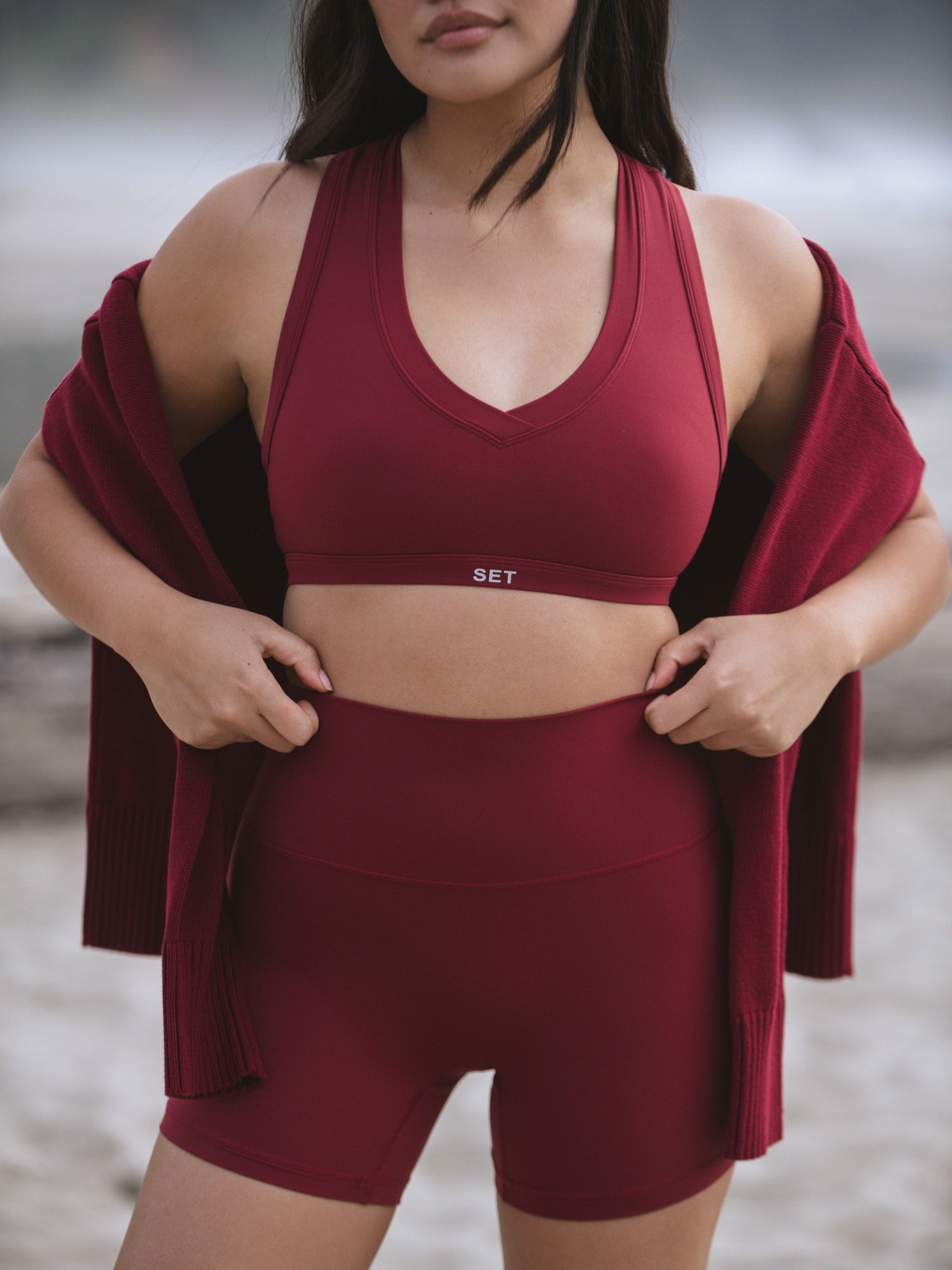 Person wearing a burgundy sports bra and shorts set with a blurred background