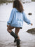 Person wearing a light blue sweatshirt with text, standing in water.