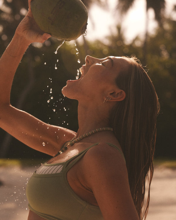 Woman drinking out of a coconut.