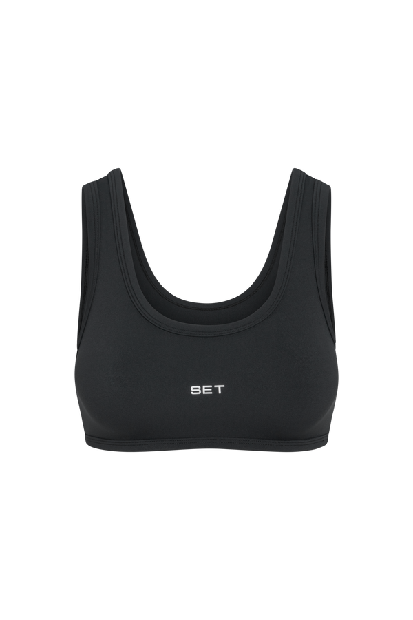 A black athletic sports bra with a scoop neckline and the brand name 'SET' printed in white on the center chest, shown against a plain white background.