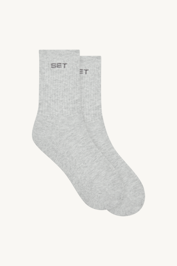 Pair of gray socks with 'SET' logo on a beige background 