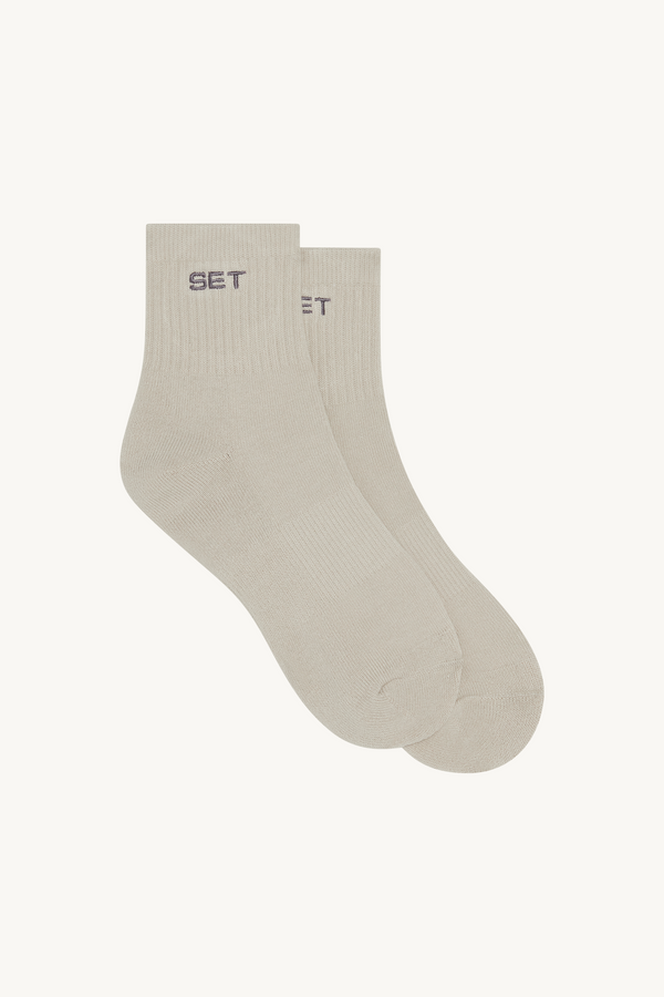 Light gray socks with 'SET' brand logo on a beige background 