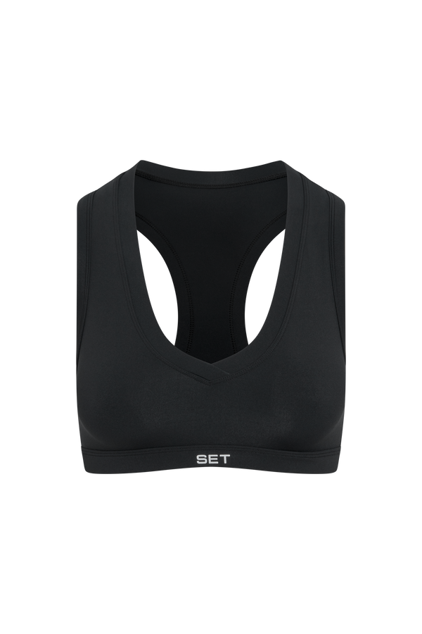 A black athletic sports bra with a wide underband and the brand name 'SET' printed in white on the front, shown against a plain white background.