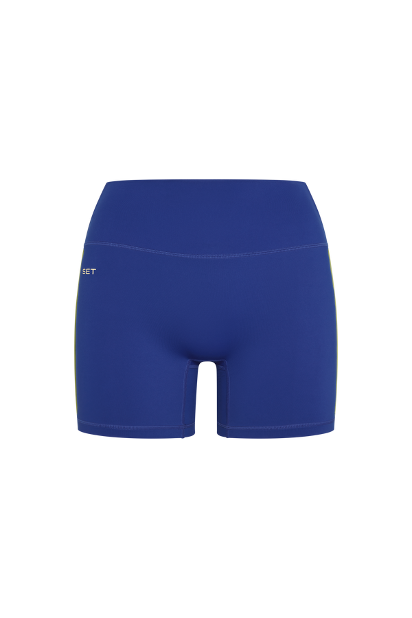 A pair of high-waisted athletic shorts in a solid royal blue color, featuring a small white 'SET' logo on the left hip, displayed against a solid white background.