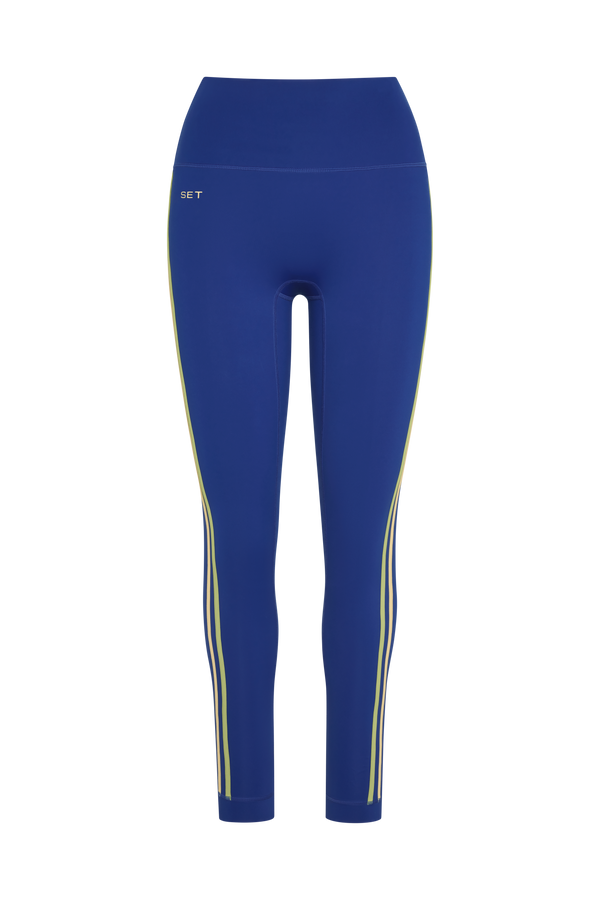 Blue high-waisted athletic leggings with yellow side stripes and a small white 'SET' logo on the upper left hip, shown against a plain white background.