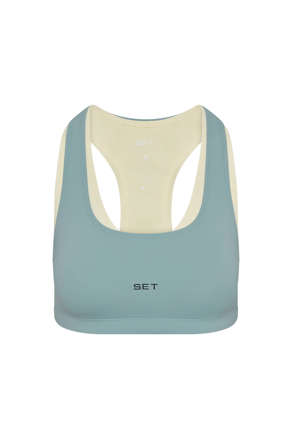 Light blue sports bra with beige straps on a white background