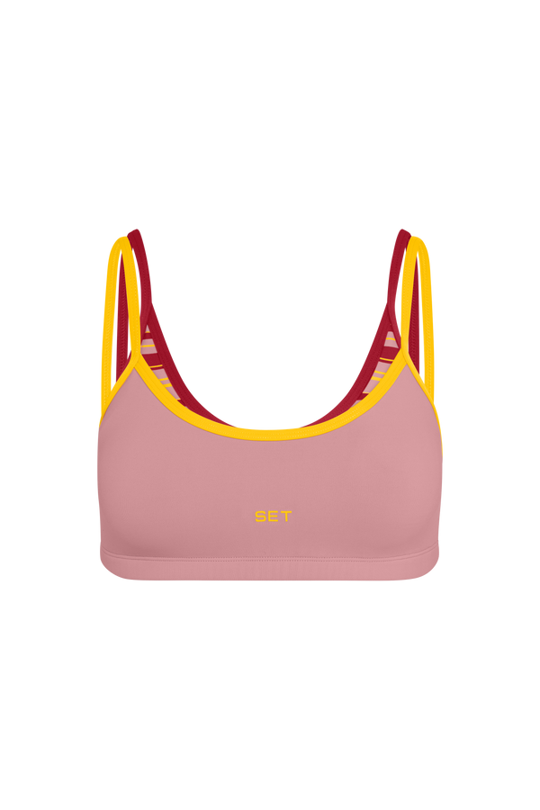 A pink sports bra with yellow and red trim and straps, featuring the brand name 'SET' printed in yellow on the front, shown against a plain white background.