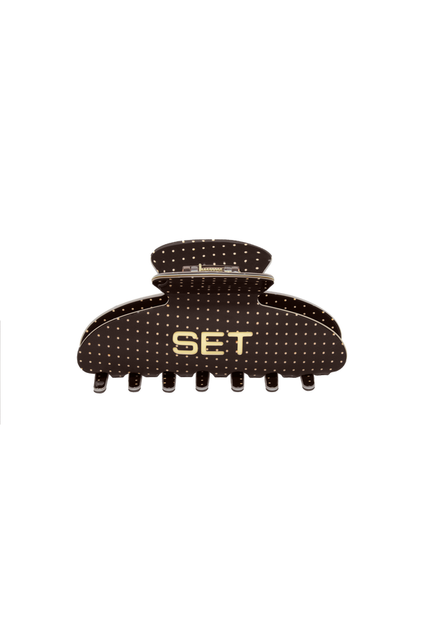 A dark brown claw hair clip with a polka dot pattern and gold lettering that reads 'SET' on the front, shown against a plain white background.