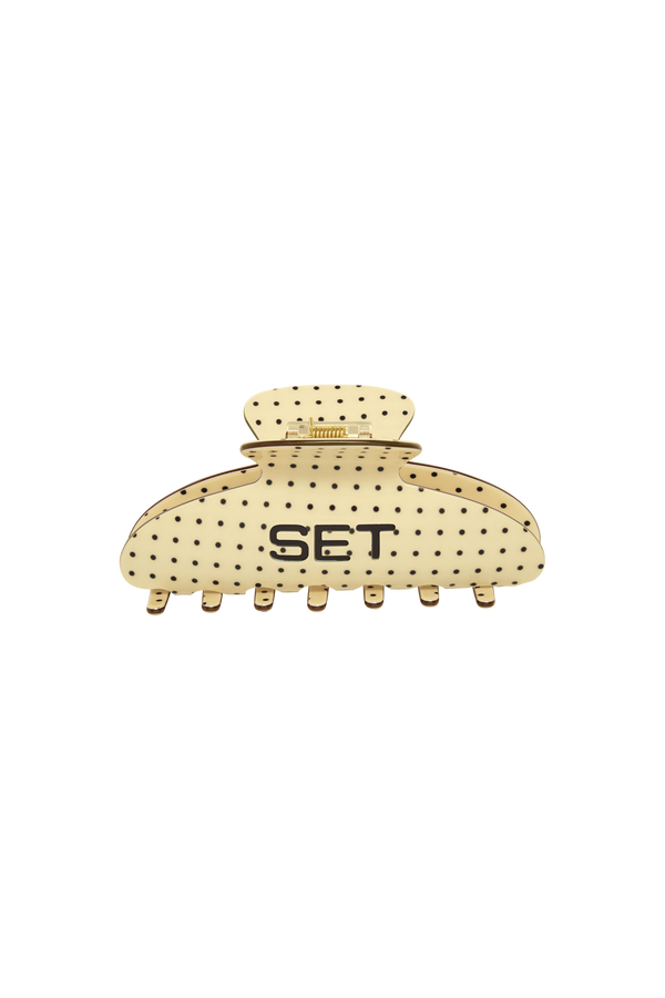 A cream-colored hair claw clip with black polka dots and the letters 'SET' printed on the front, set against a plain white background.