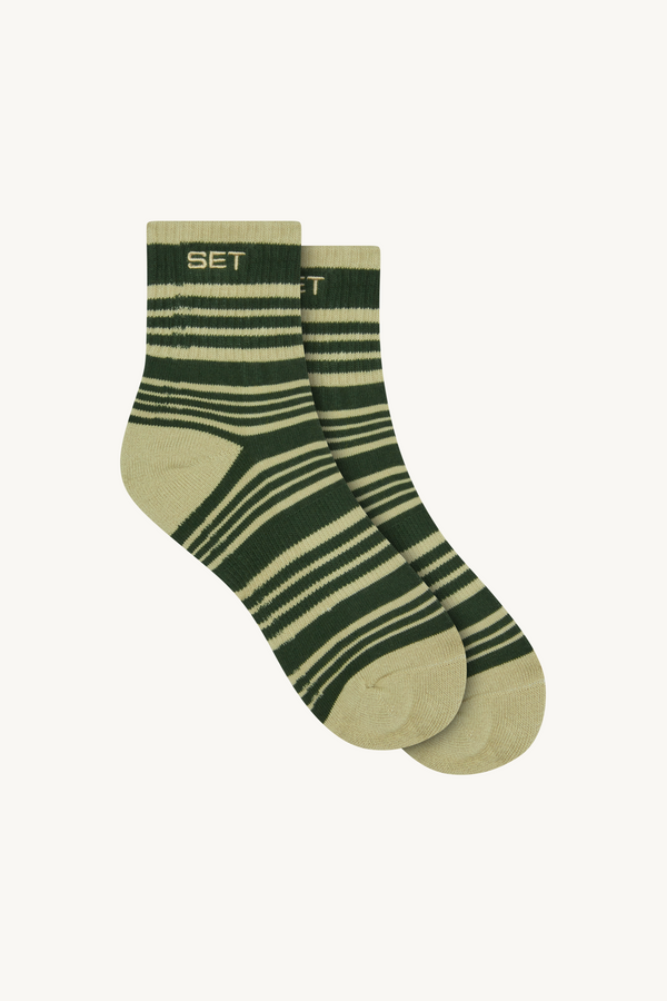 Green striped pair of socks on a beige background