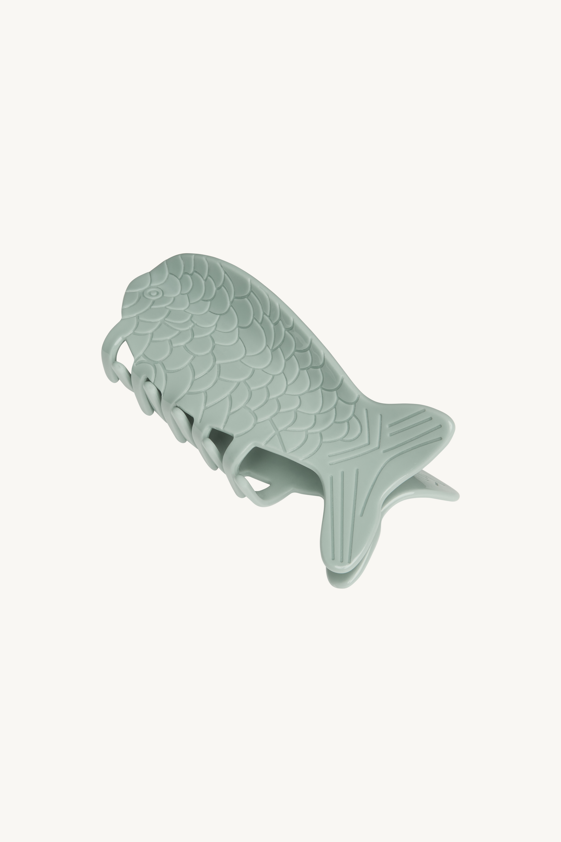 Fish-shaped green claw clip on a white background