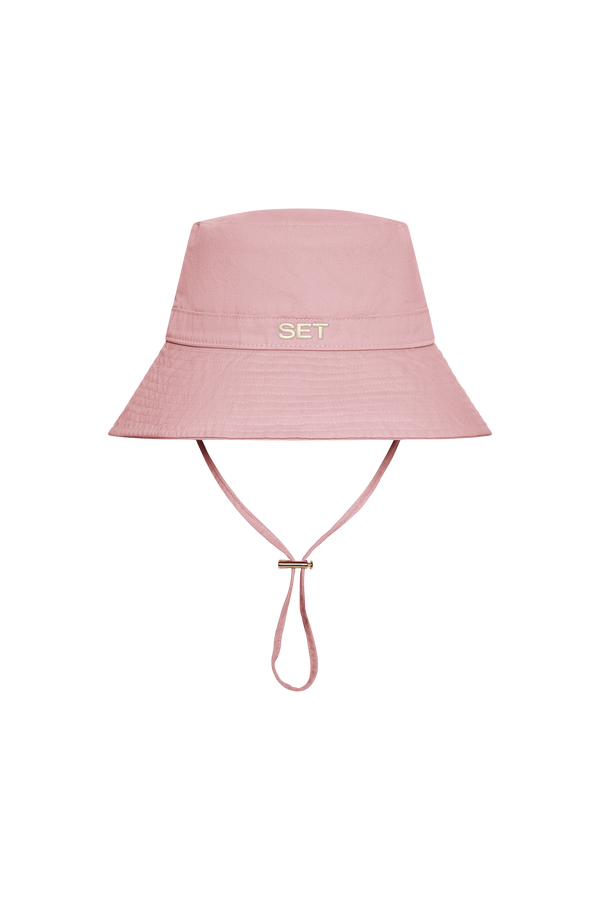 A light pink bucket hat with a chin strap and the word 'SET' embroidered in red on the front, shown against a plain white background.