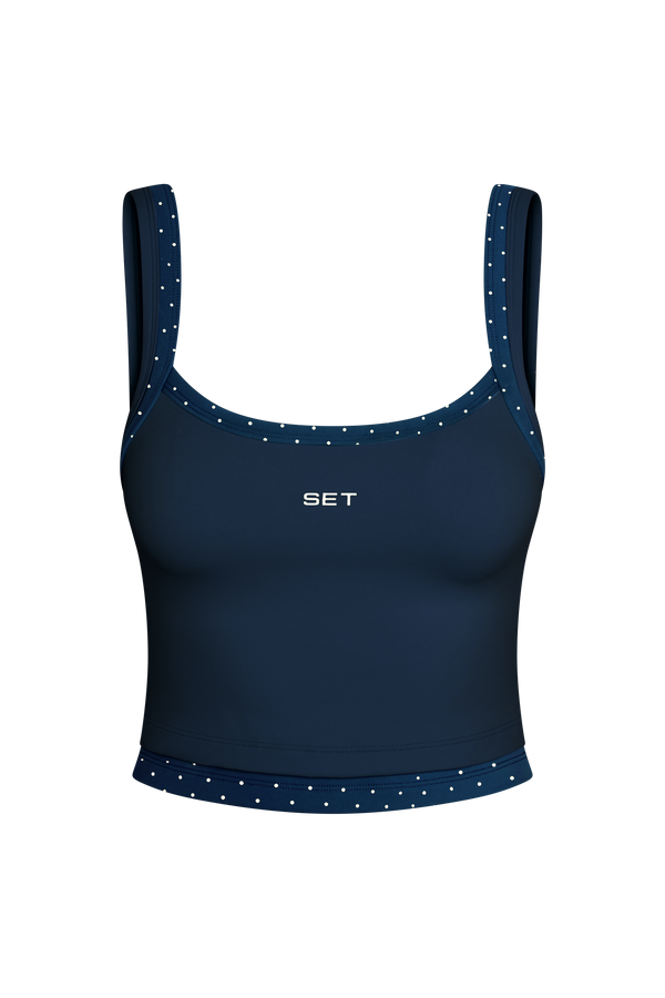 Navy blue sports bra with white polka dots on a white background