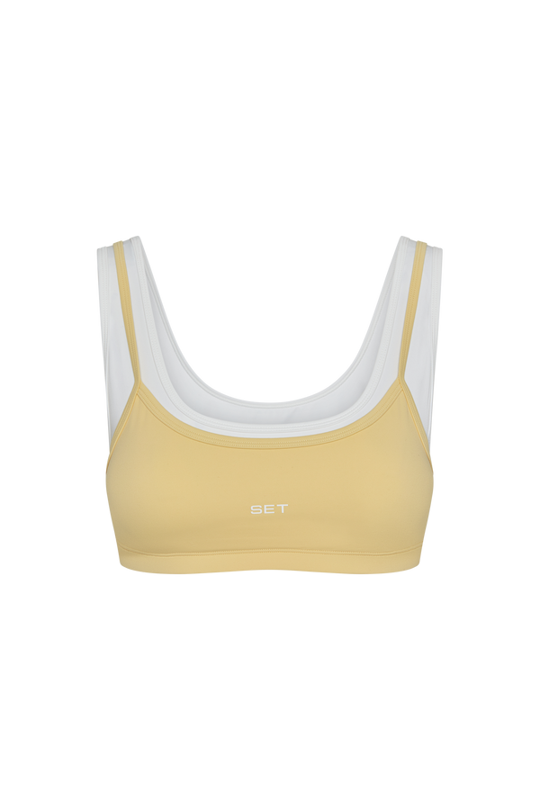 Yellow sports bra with white accents on a white background