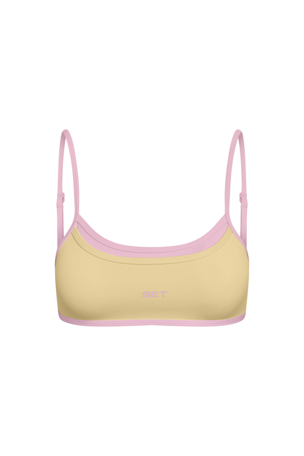 Yellow bikini top with pink straps on a white background