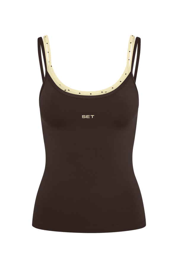 A dark brown ribbed tank top with cream-colored shoulder straps and a small gold 'SET' logo on the chest, shown against a plain white background.