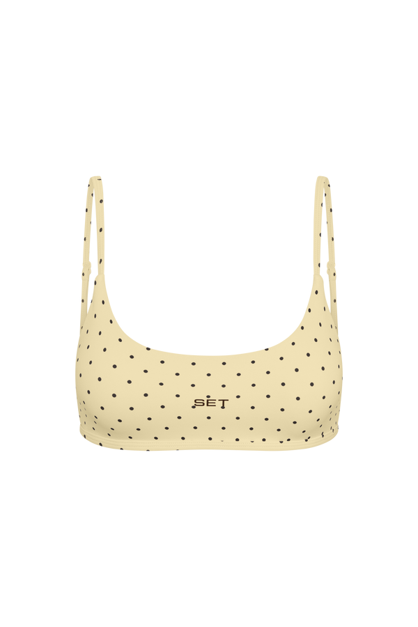 A light beige bikini top with black polka dots and the brand name 'SET' printed in black on the center chest, shown against a plain white background.