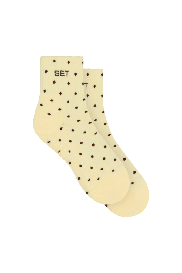 A pair of cream-colored ankle socks with a small dark brown polka dot pattern and the word 'SET' printed on the cuff, shown against a plain white background.