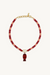 Necklace with red beads and a gold fish pendant on a white background