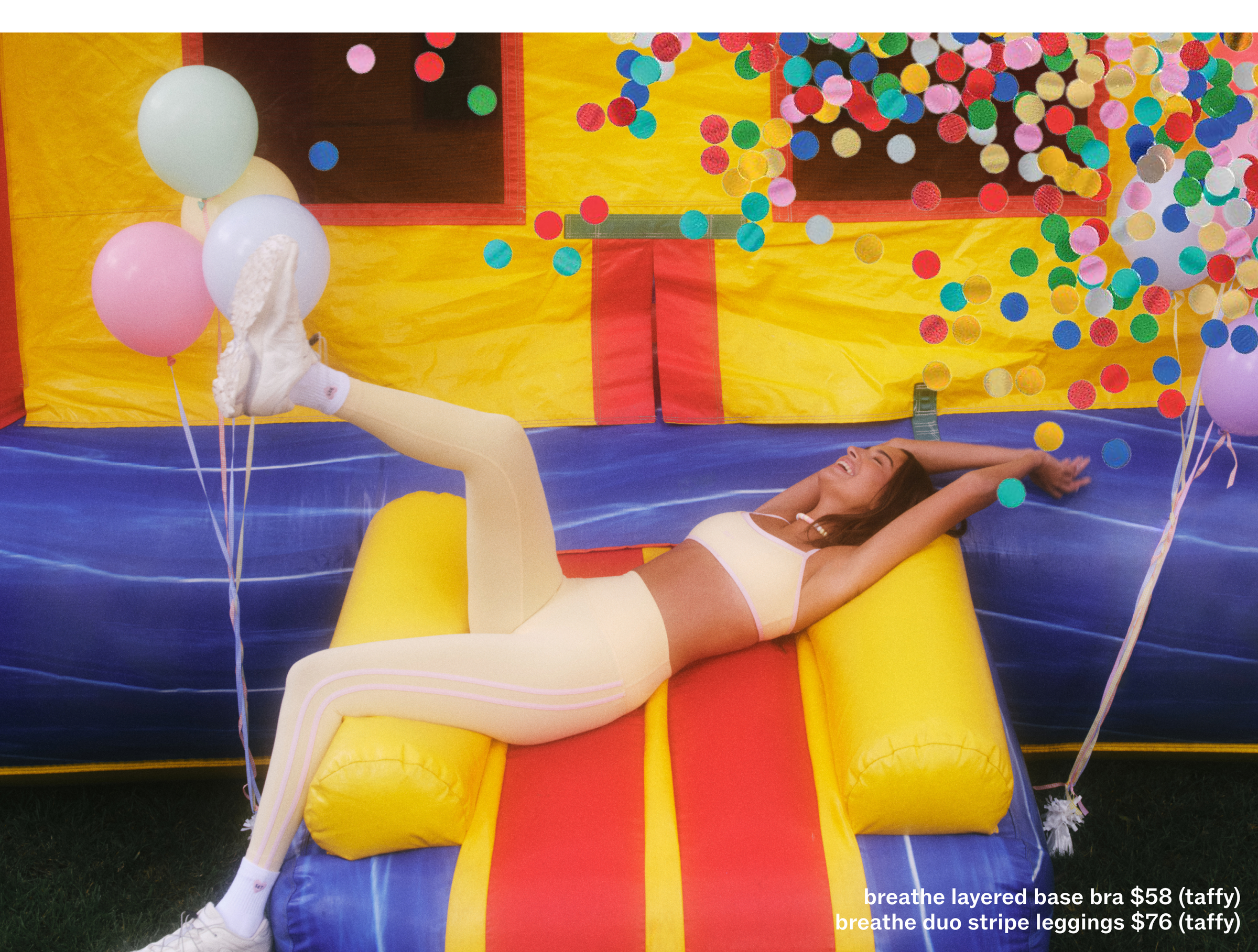 Person lying on a colorful inflatable slide with balloons and confetti