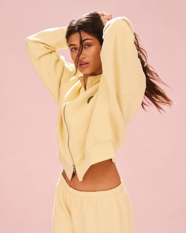 Woman wearing a light yellow outfit against a pink background