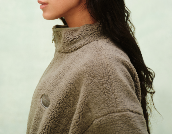 Person wearing a brown fleece jacket against a light background