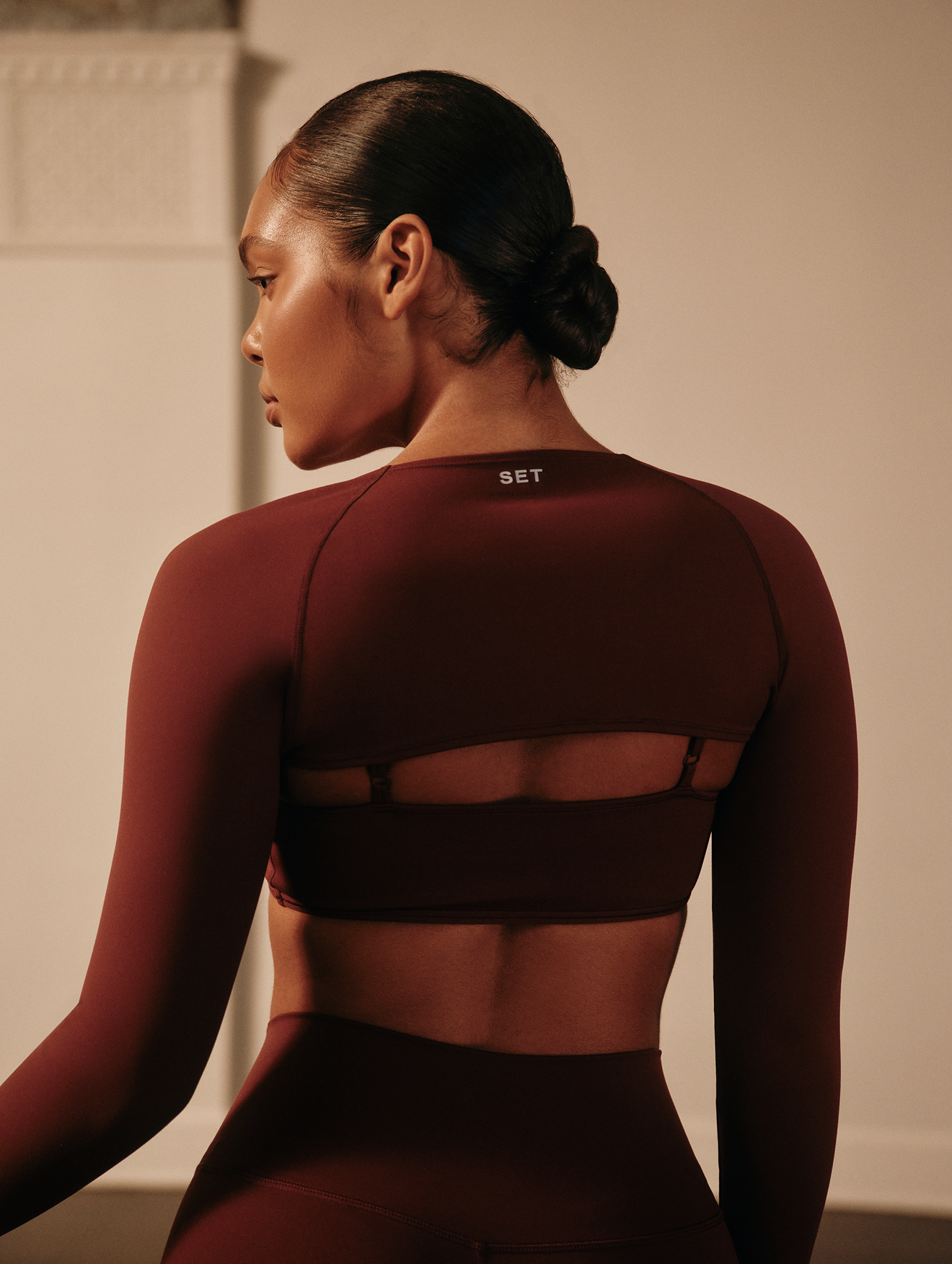Woman wearing a maroon athletic outfit with 'SET' branding.