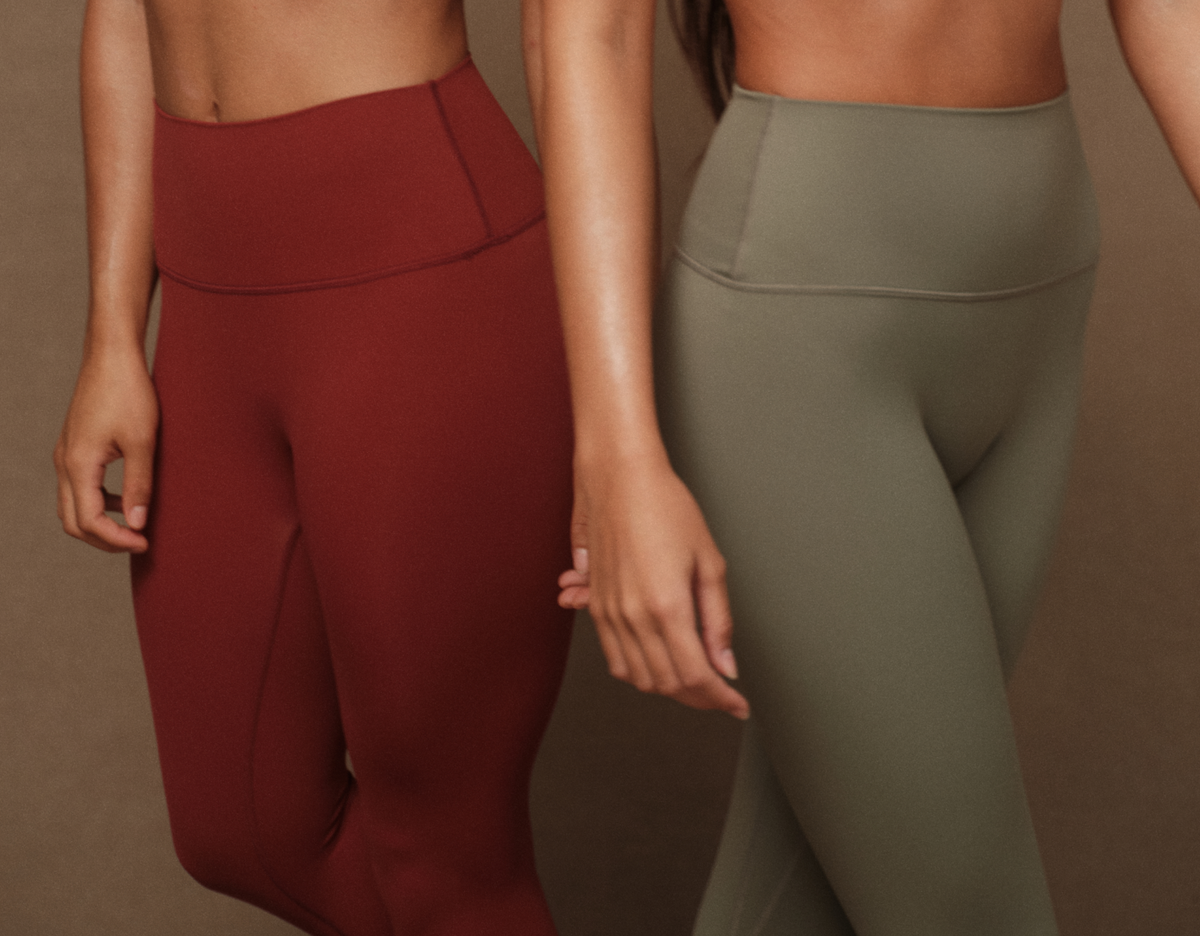 Two pairs of high-waisted leggings in red and green on a brown background