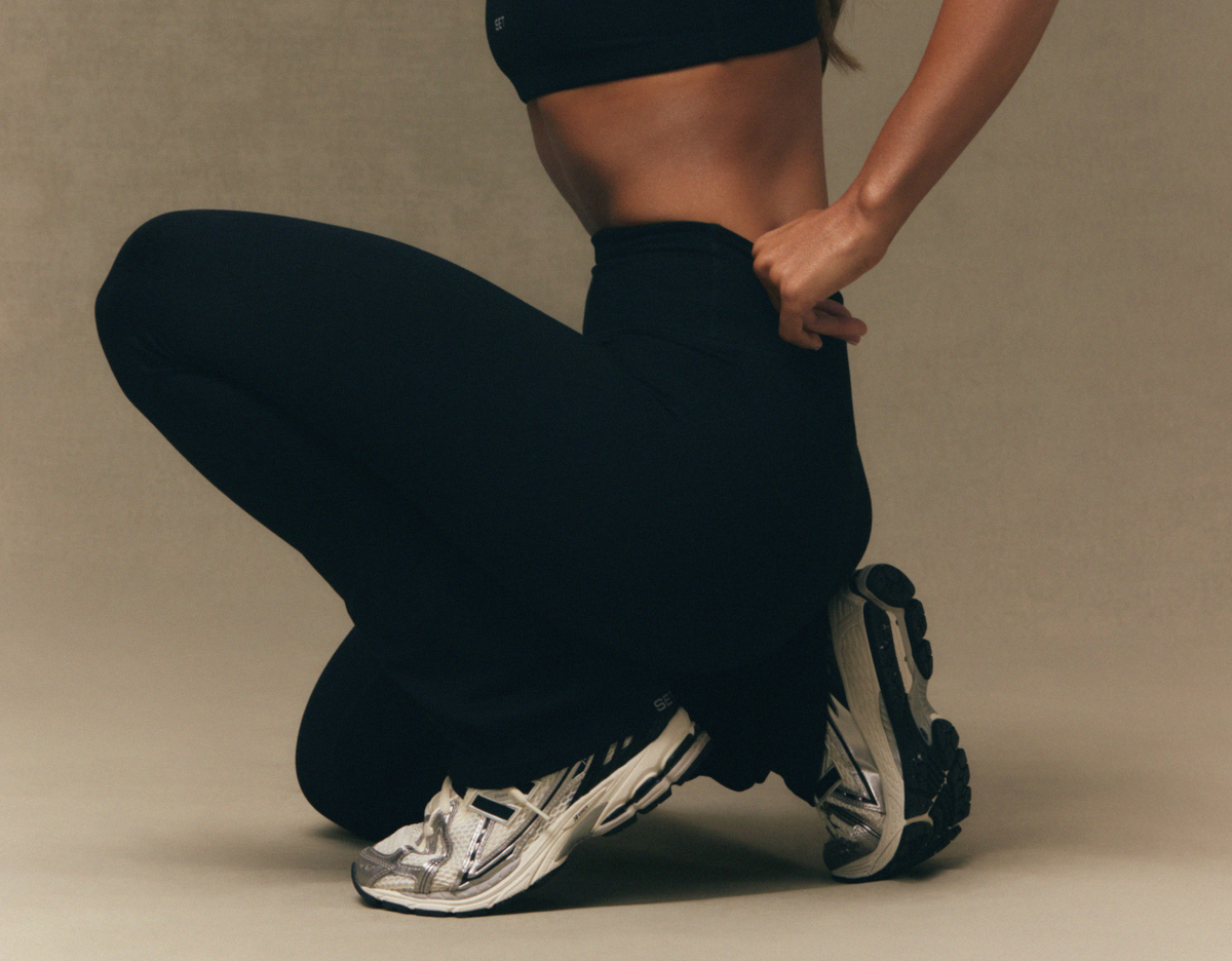 Person wearing black athletic pants and silver running shoes on a beige background